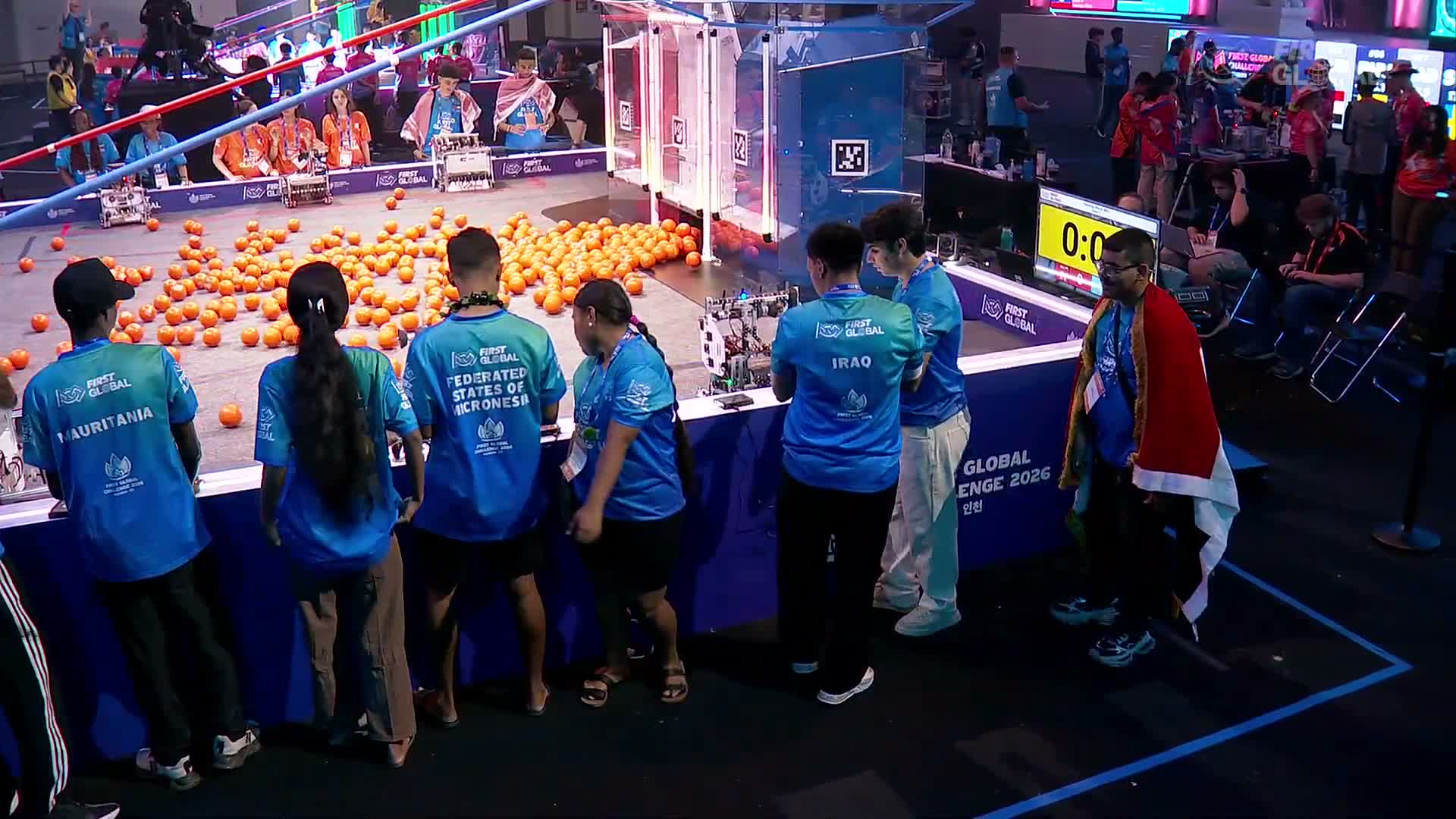 Students from FSM, Mauritania and Iraq stand beside the robotics field before Match 300.